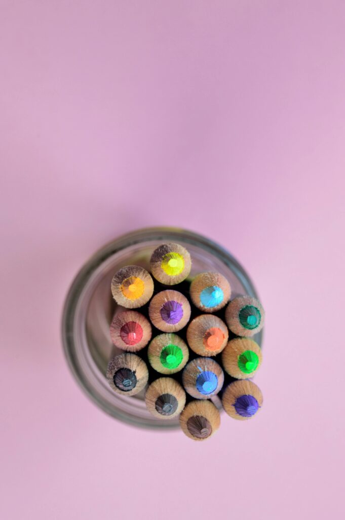 Colorful pencils in a glass jar from above on a pastel backdrop. Perfect for art and educational themes.